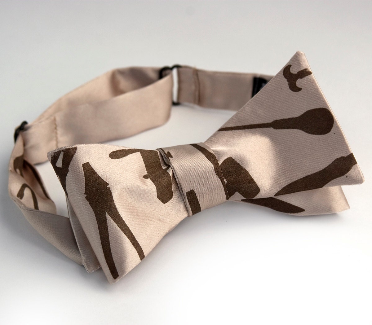 Tool bow tie. Khaki fabric, self-tie. "Weapons of Mass Construction." Chocolate brown print.