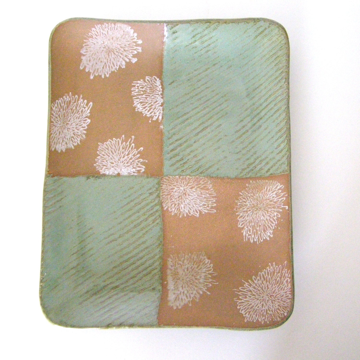 Green tray with white blossoms on brown clay