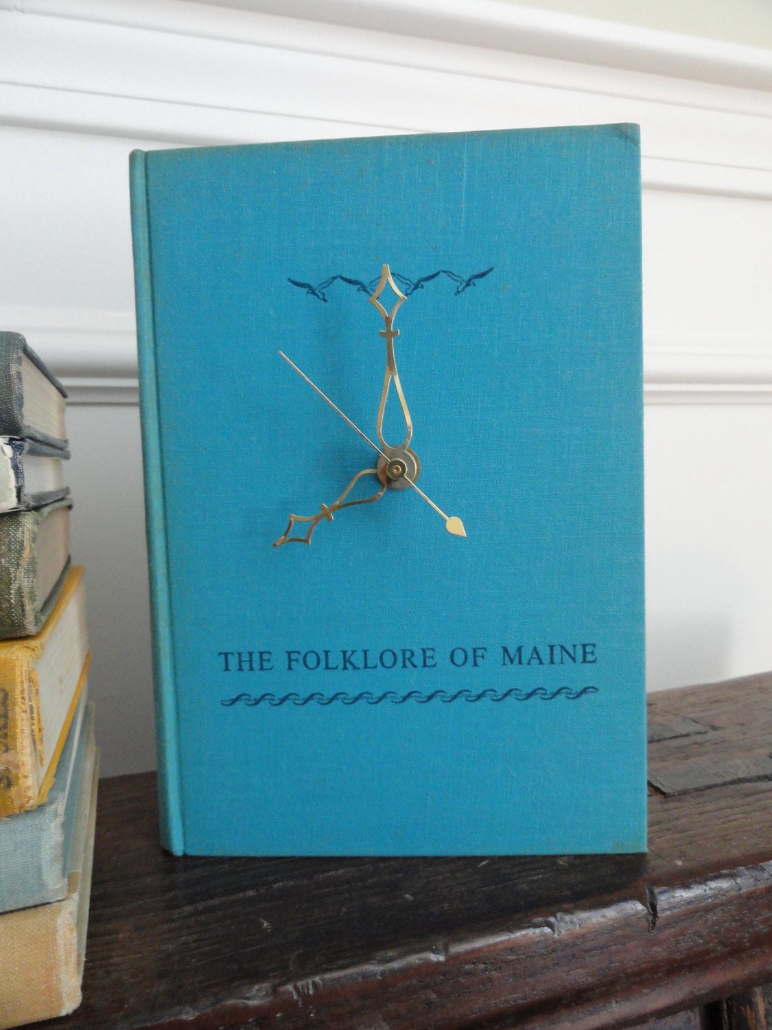 Book Clock, The Folklore of Maine, turquoise blue cover with navy blue title & seagulls, brass clock hands