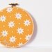 Embroidery Hoop Decor, Wall Art. "But... How" Hand Stitched on Bright Orange Starburst Fabric. Embroidered by Merriweather Council