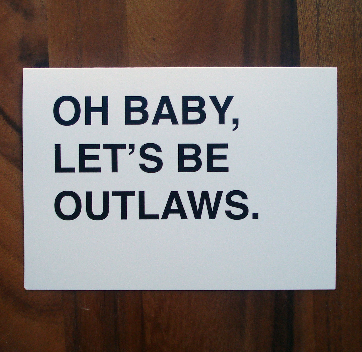 oh baby, let's be outlaws greeting card - black