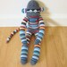 Earthy sock monkey with sky blue, brown, red, black, and white stripes - plush doll