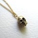 Gold skull charm necklace on delicate 14k gold plate chain, satin finish