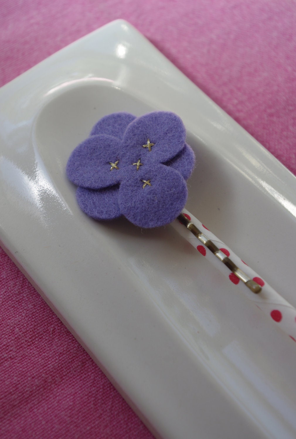 Purple wool felt flower hair clip with gold stitching.