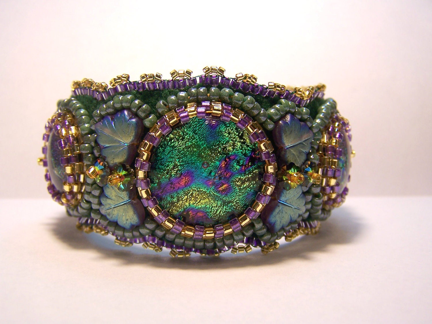 Colorful bead embroidered cuff bracelet featuring handcrafted dichroic glass cabochons and froster glass leaves and Japanese seed beads.