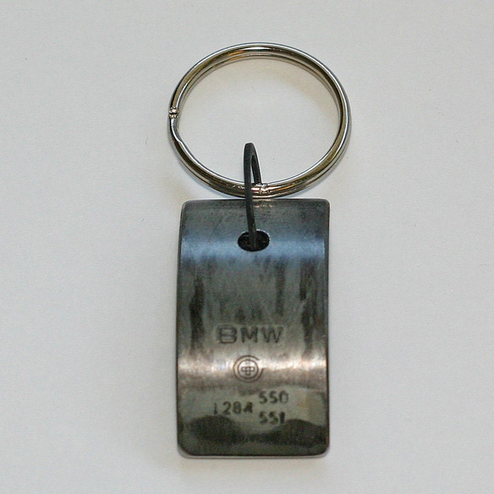 Car Engine Part KEYCHAIN - salvaged BMW part with original stampings of logo and part numbers.  Black velvet backing.