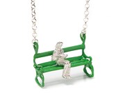 Green and silver pendant with a nice girl sitting on a Green bench and reading a book