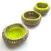 A set of three natural cotton crocheted jewellery baskets, with contrasting bright neon thread