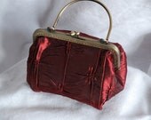 Small red textured silk purse with steel frame.