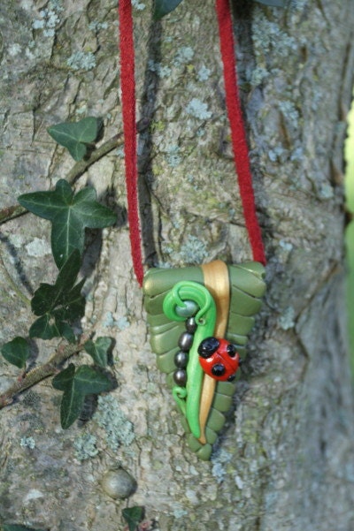 Freya's ladybird necklace on red suede thong. Polymer clay lady bug on leaf with pearls.