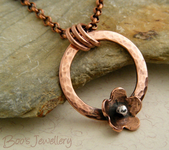 Antiqued copper necklace featuring a hammered circle pendant with a copper flower