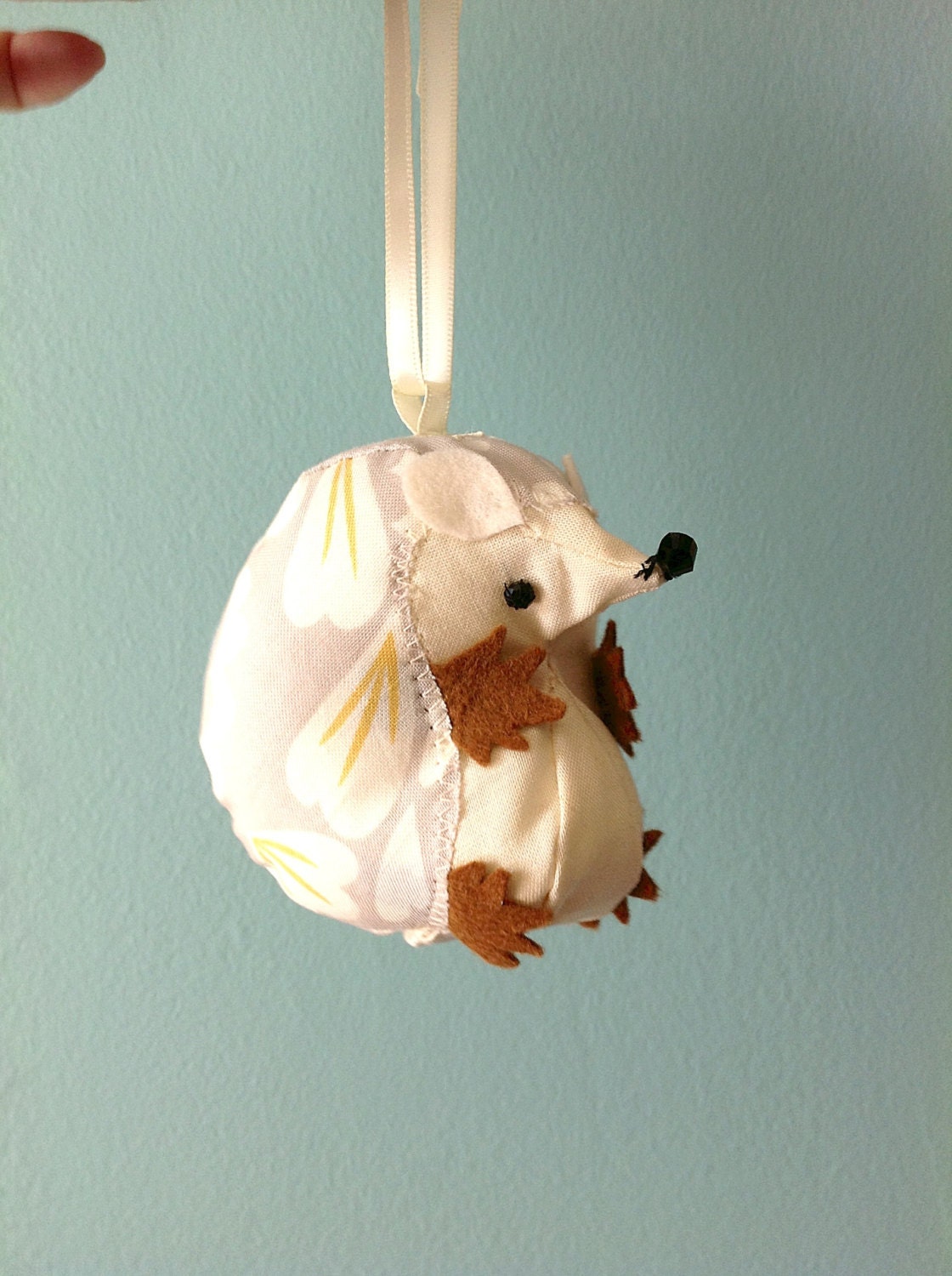 Little hedgehog ornament in shades of beige and offwhite.