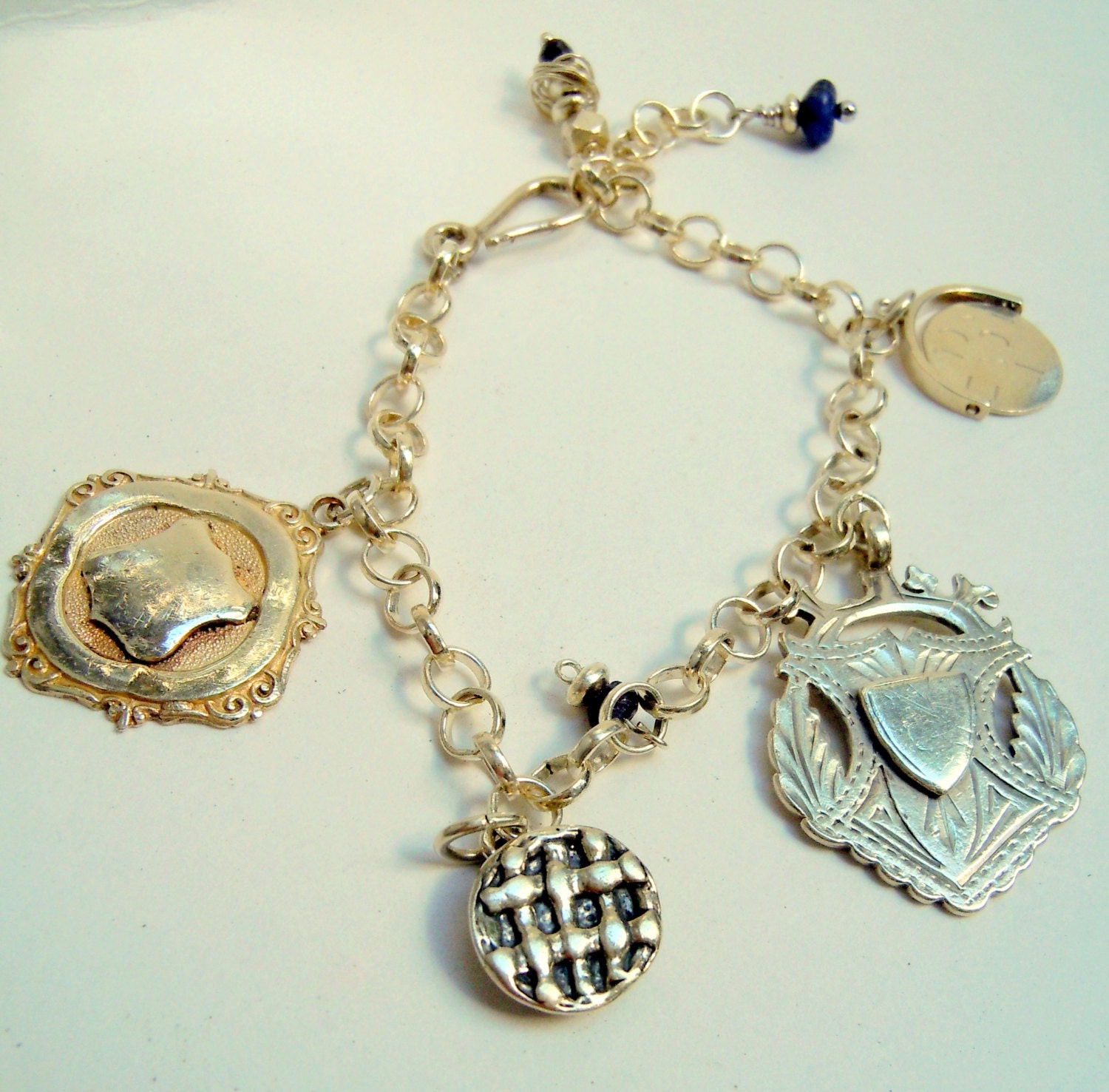 Sterling silver charm bracelet with antique english sterling silver medals an sterling apple pie charm and an I love you spinner