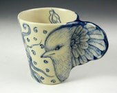 Hand made blue and white coffee or tea cup with bird wing and face