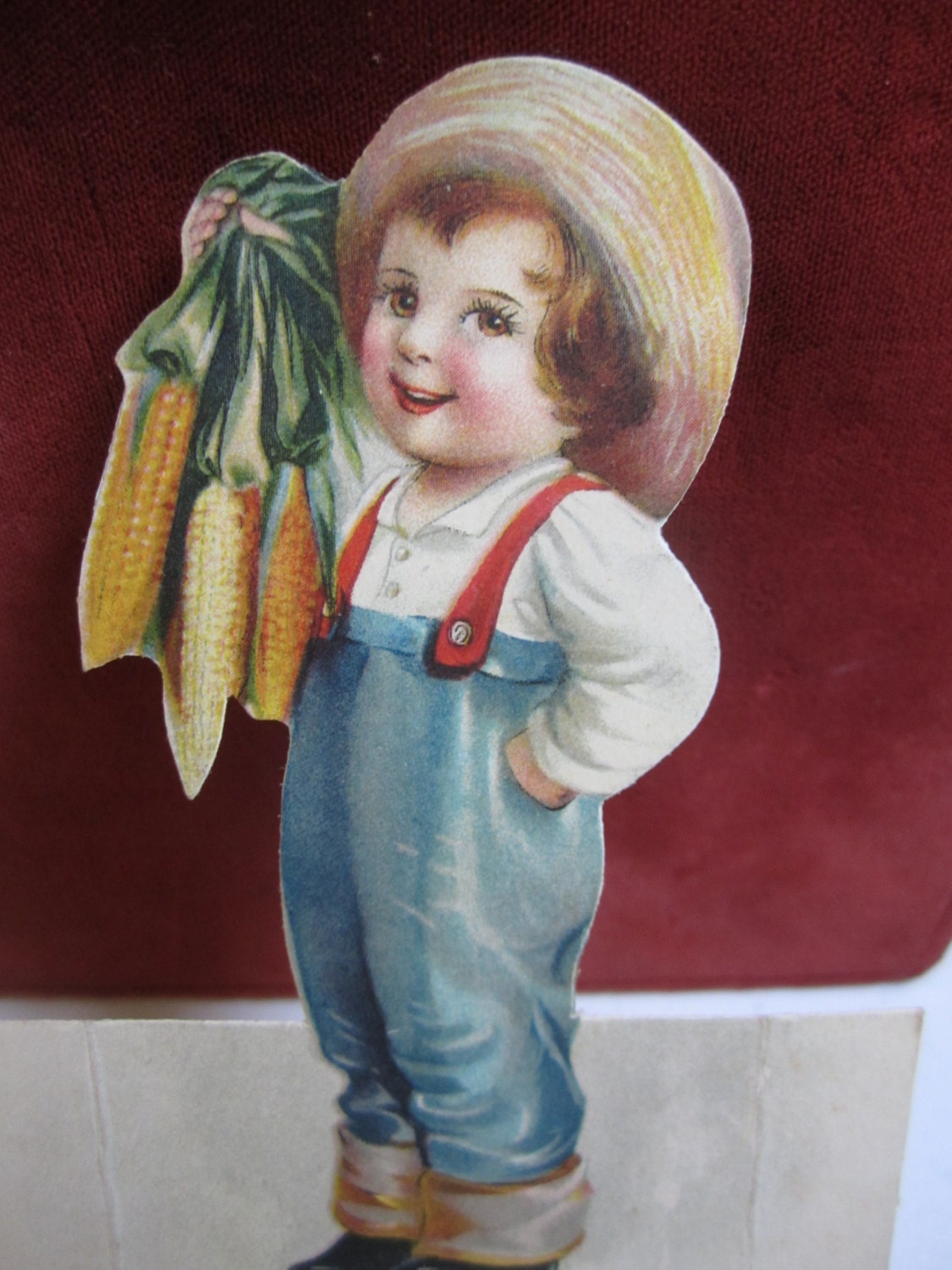 Adorable 1910's-20's die cut thanksgiving place card unused little boy dressed in cuffed jeans straw hat suspenders holding  corn on the cob - puffadonna
