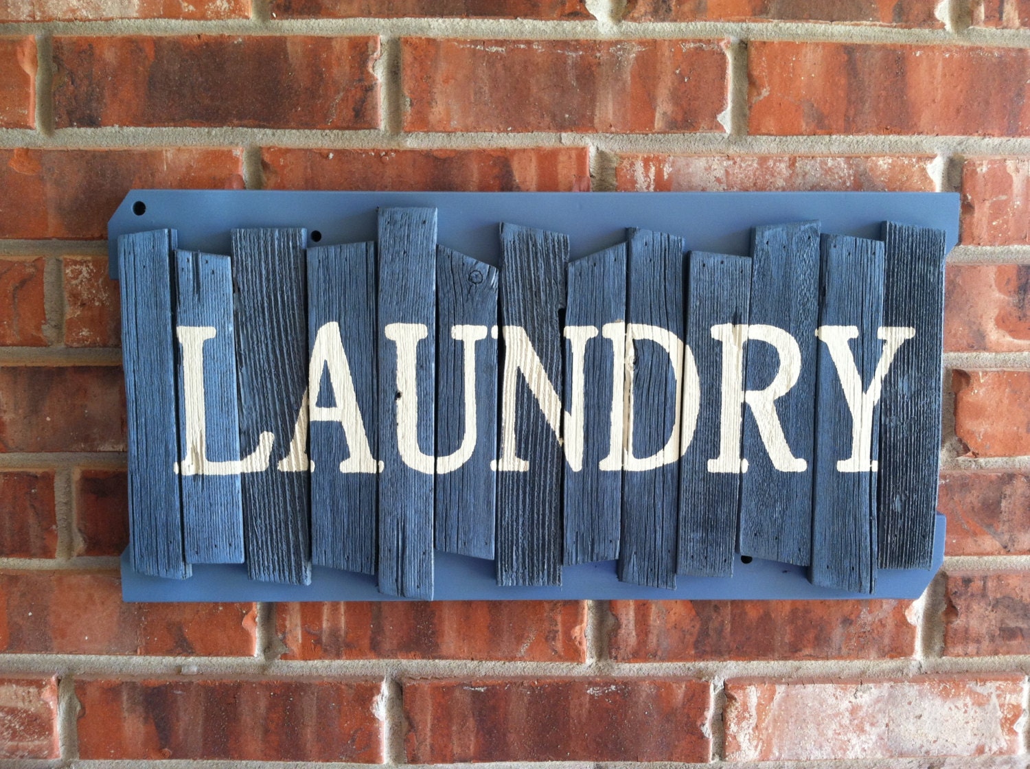 LAUNDRY in white block letters on a handmade rustic random cedar wood sign painted slate blue