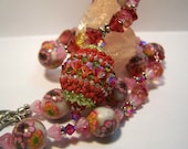Beaded bead pendant on floral necklace featuring hand made beads in rust pink and green