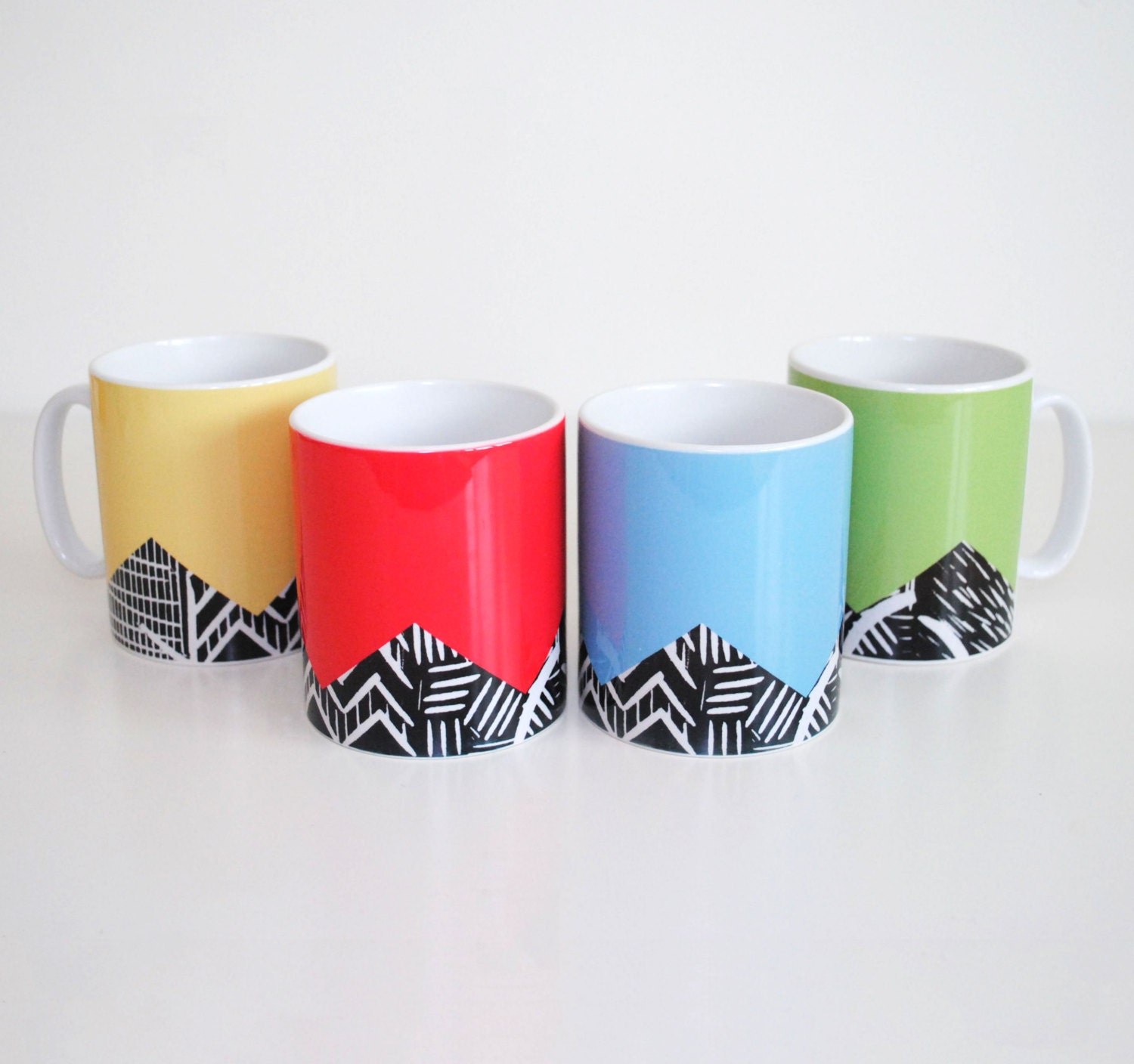 Four colourful mugs with lino print design