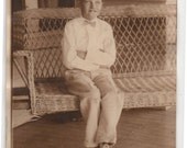 VINTAGE PHOTO - a cute young bucktoothed Whippersnapper with his slicked hair and bow tie sitting on wicker porch swing - cool shoes too