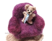 Miniature amigurumi teddy bear with  a purple arm chair and crochet blanket
