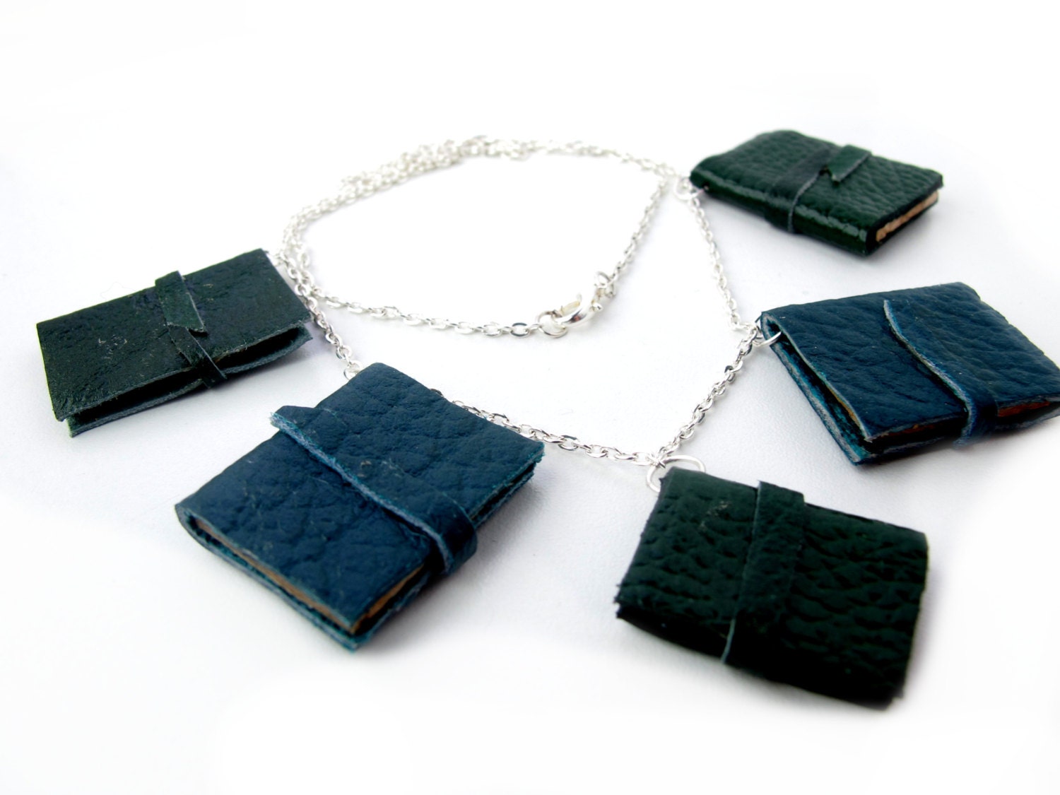 Book necklace, five blue and green decorative leather journals on silver chain.