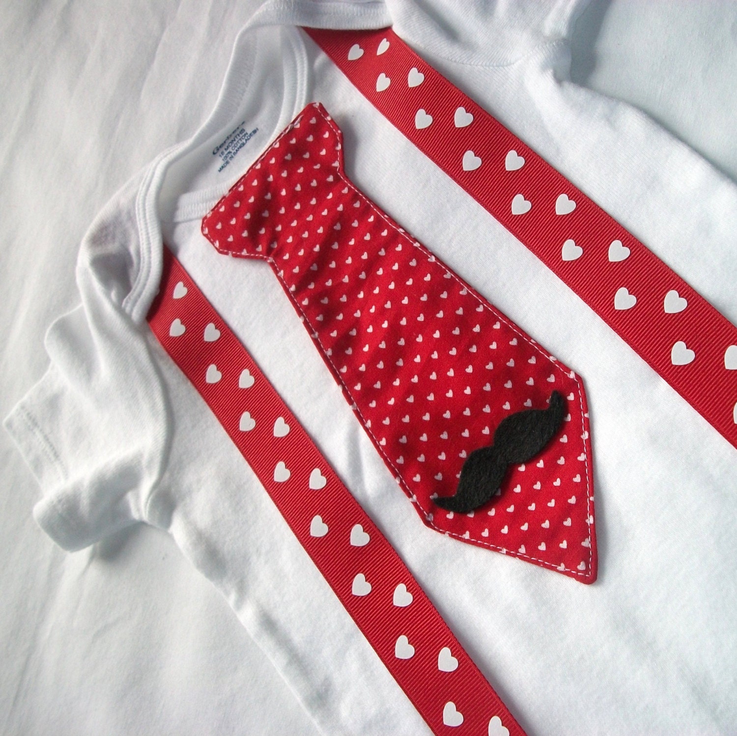Listing includes onesie or T-shirt with Valentine's Day red with white hearts tie, felt mustach and suspenders. Little man mustache party.