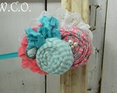 the CORA Coral and Aqua Rolled Fabric Rosette Headband with Eyelet Lace and Seam Binding Bow