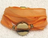 Silk Ribbon Whirly Wrap Bracelet in Carrot Orange with a ceramic abstract accent piece Karen Blixen Museum