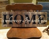 Home Is Wherever I'm With You in black and cream letters on a natural weathered cedar fence picket sign