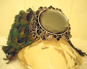Couture dog collar. Center black faux gem  sculpted metal overlay and Peacock feather surround.