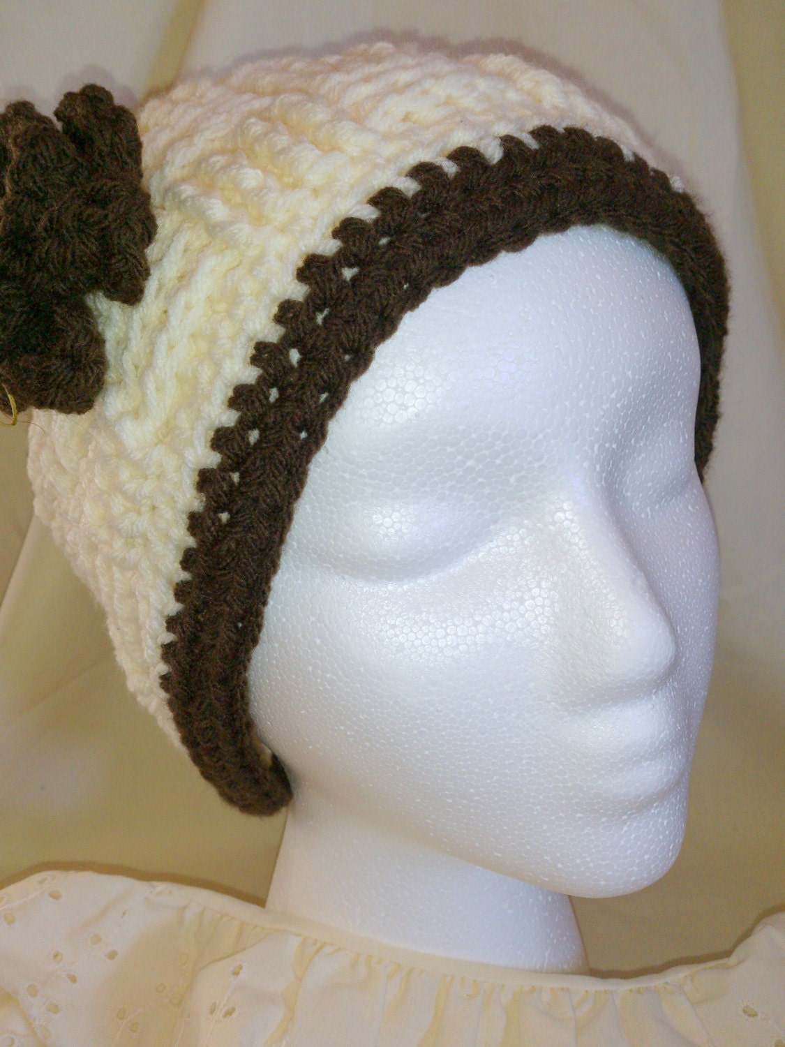White skull cap beanie w/ flower & brown rim.