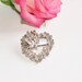 White metal MASJ brooch from 1990 in shape of heart with humming bird, silver looking, flowers.