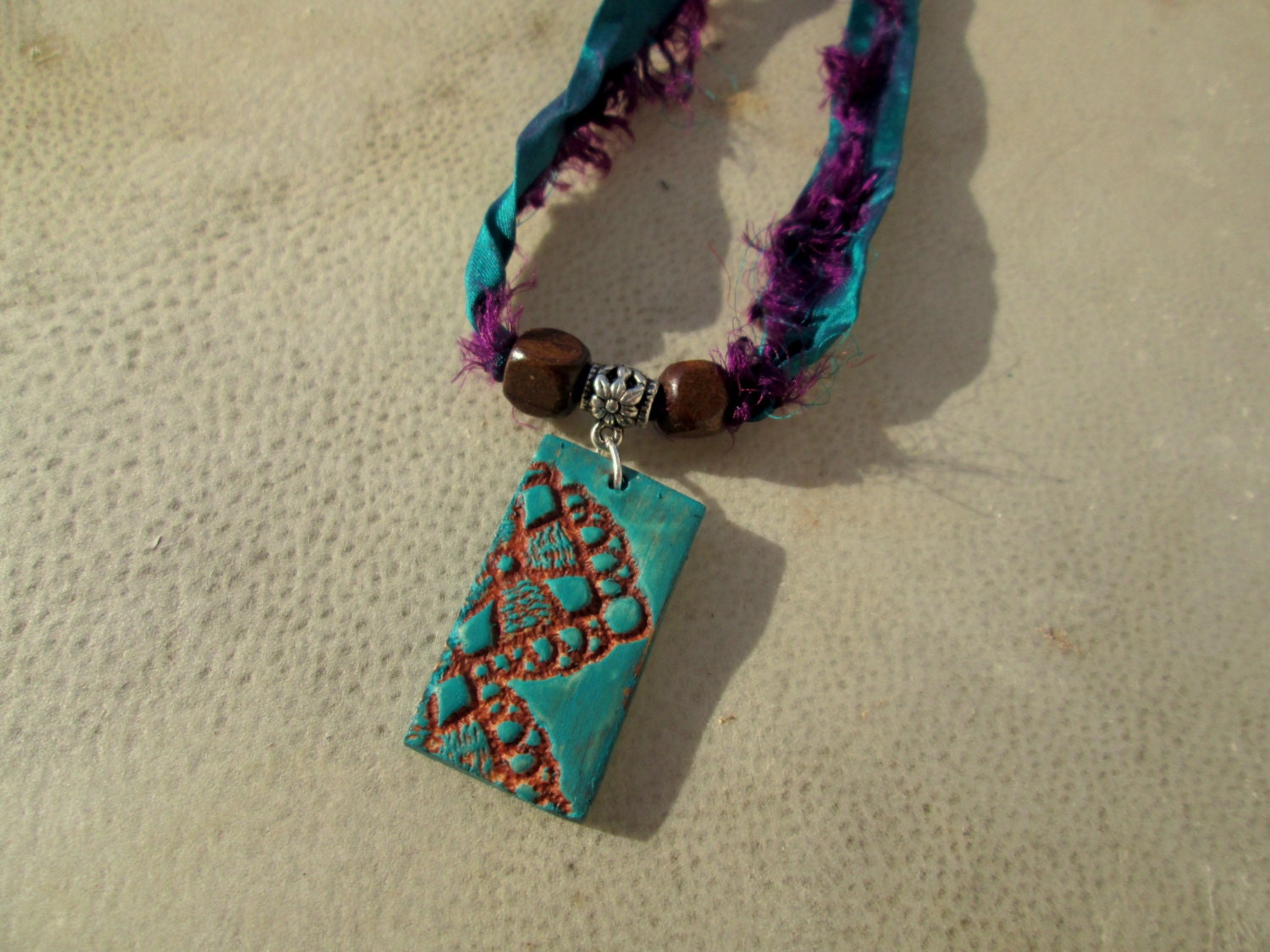 Alela. Lace Textured Polymer Clay Pendant on Recycled Sari Silk Ribbon. Turquoise, Brown, Purple. Wooden Beads.