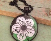 Green and black pendant necklace with white flower. Black  finish. 1 inch