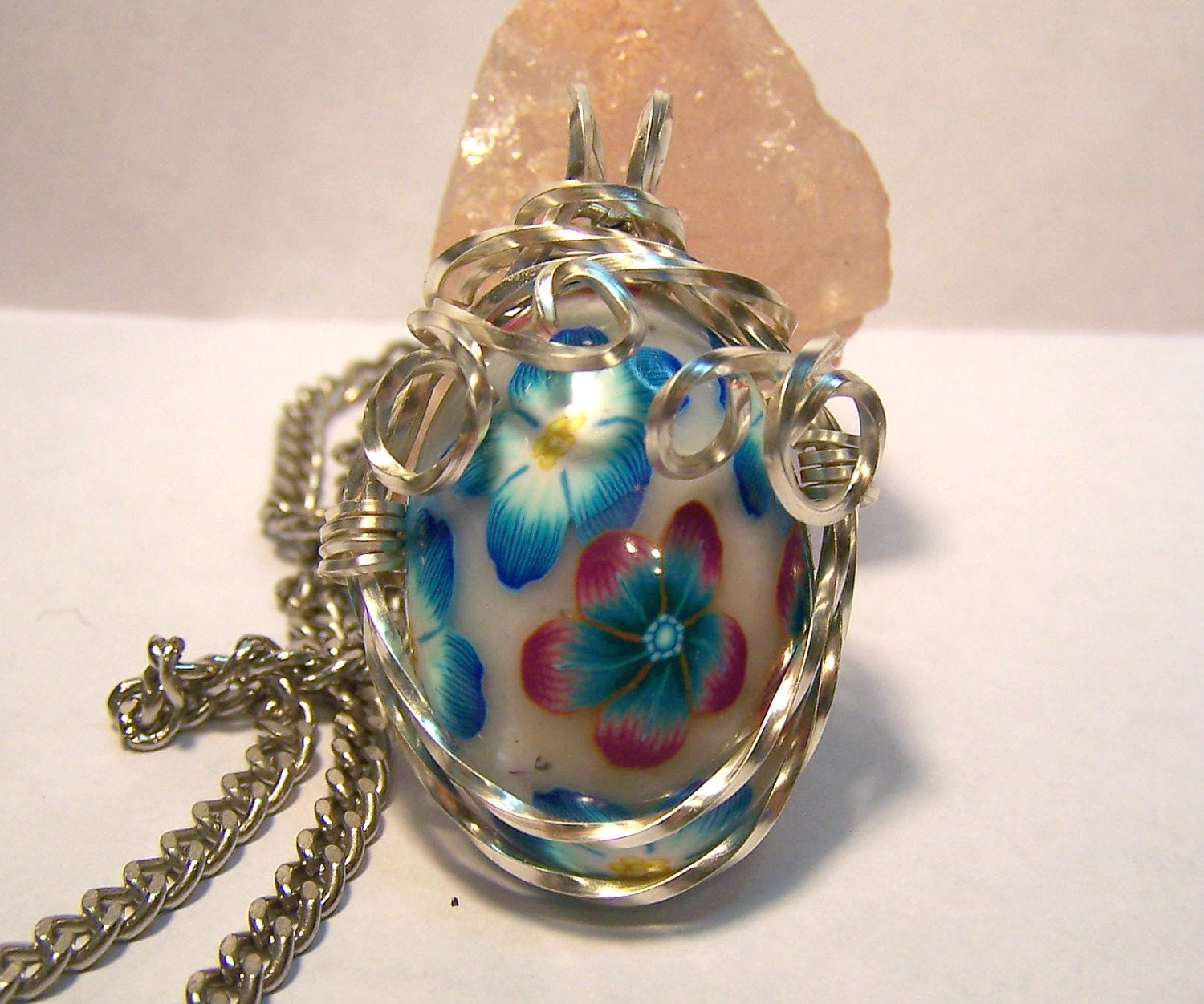 Wire wrapped blue and red floral pendant on chain.