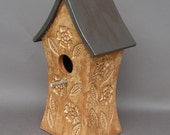 Tall mottled brown stoneware decorative birdhouse, covered with flowers, with a gold roof