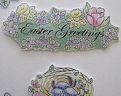 Two Magnets with Easter Greetings surrounded by Tulips and Daffodils and a Bird Nest Adorned with Flowers, Feathers, and Three Blue Eggs