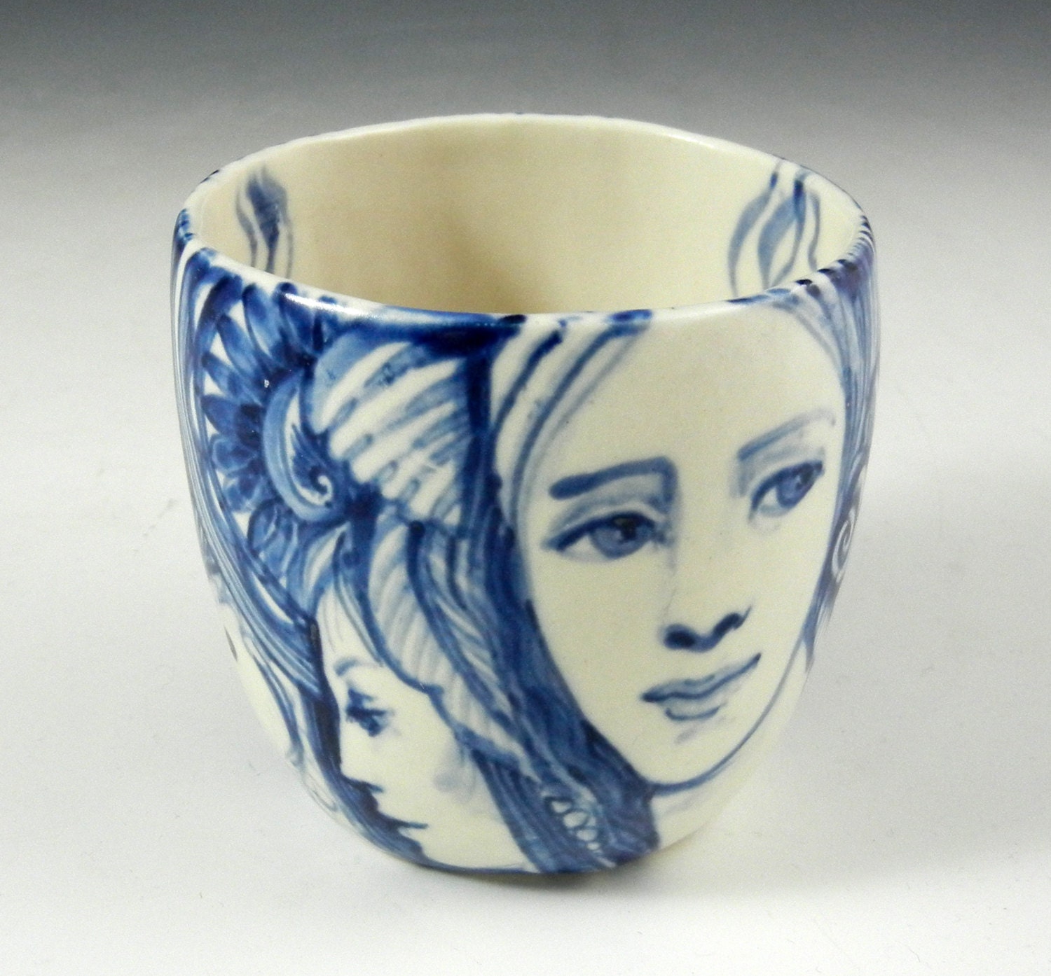 blue and white story cup with faces,cats,a fish and the word "Imagine"
