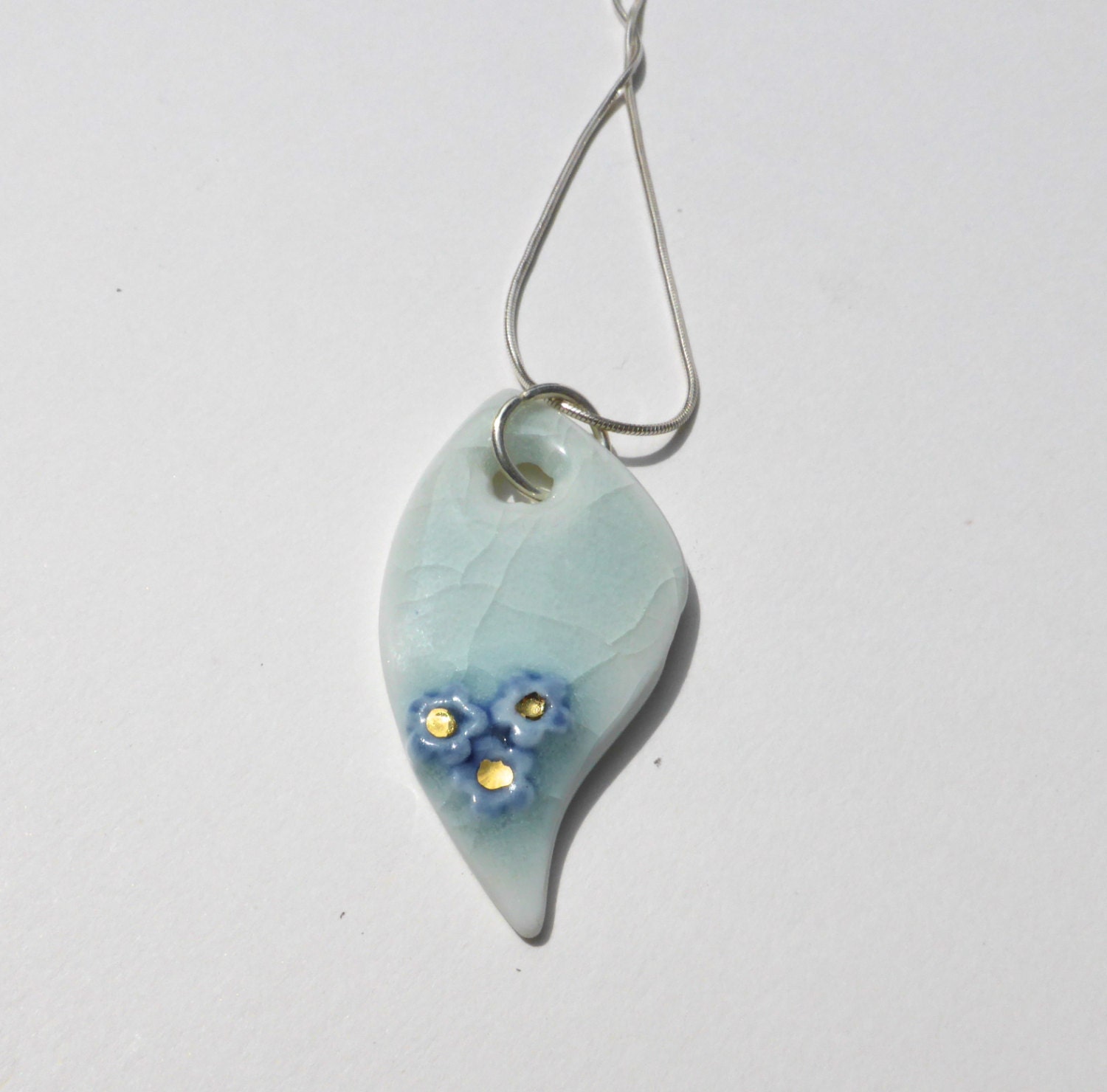 Leaf shaped porcelain pendant, pale green crackle celadon glaze, with blue and gold flowers