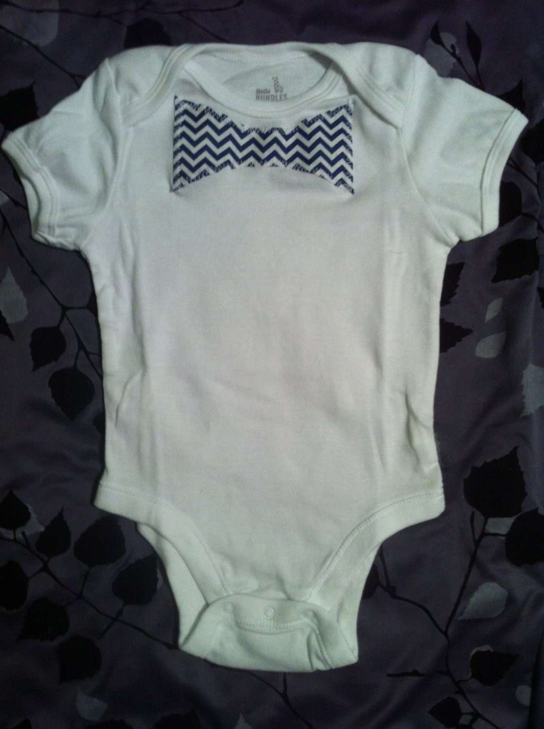 White onesie with denim/chambray colored small chevron pattern bow tie or neck tie