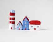 Three little clay houses and a striped lighthouse - blue, white and red