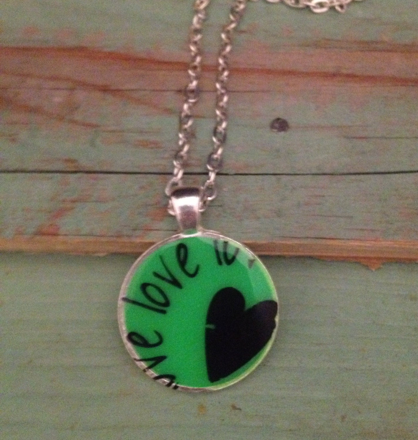 Green pendant necklace with heart and 'love' quote. Silver  finish. 1 inch