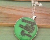 Bright green resin pendant necklace with a black bird and quote 'born to stand out'. Large round 38mm