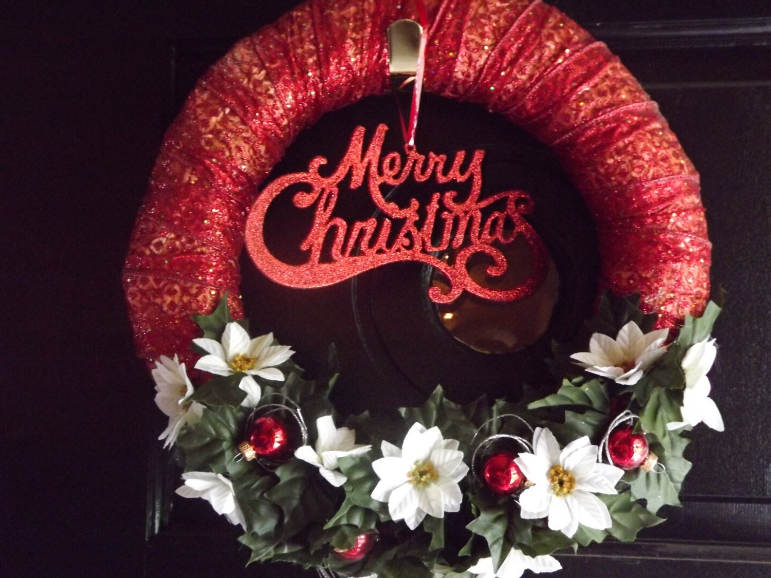 Merry Christmas greeting wreath with garland, white poinsettias, red mini ornaments, and silver accents