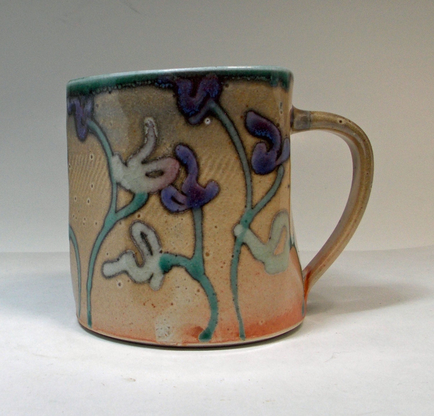 shino cup with purple and green flowers and a jade green interior - BlackForestPottery