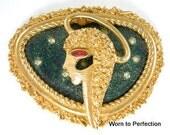 A Boucher astrological brooch for that special Virgo in your life. Boucher brooch is signed Boucher with the copyright symbol. It also is stamped VIRGO on the back with the maker's number. This brooch is marked 9875P. It measures 1-7/8 by 1-1/2 inches. In very good condition with nothing to point out or mention other than it's beautiful! High gold brushed finish is in very good condition. Multi-layers float the female's face over a greenish blue background with cut outs that remind me of a constellation against a dark sky.