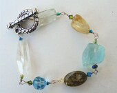 Natural gemstone bracelet consisting of faceted and Citrine, smooth Grossular Green Garnet, Aquamarine and Swarovski crystals.