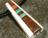 Silver pendant inlaid with dinosaur bone, red coral and Australian opal.