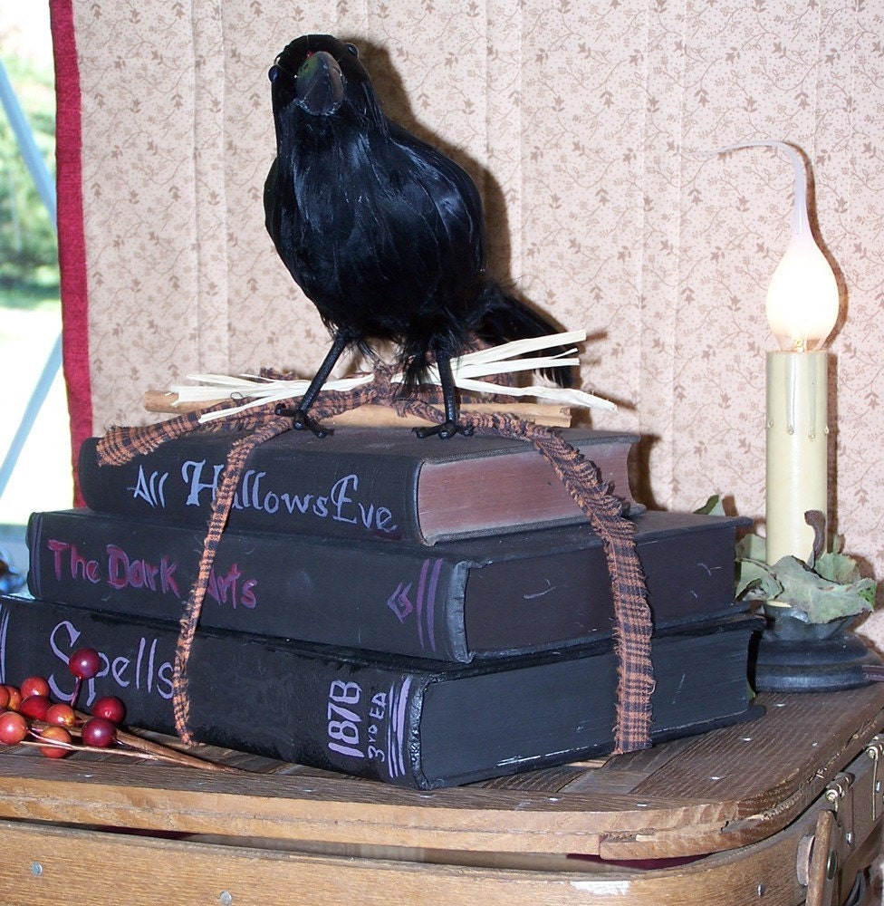 a crow sitting on top of a  stack of altered books books  spells the dark arts all hallows eve