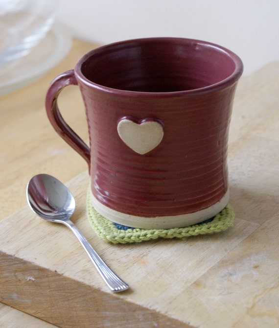 Picture of a red pottery mug with small white-brown heart on it